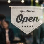 Welcoming open sign displayed in a shop window with blurred background.